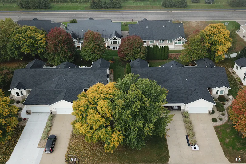 Neighborhood of shingle-roofed houses and fall trees seen from above